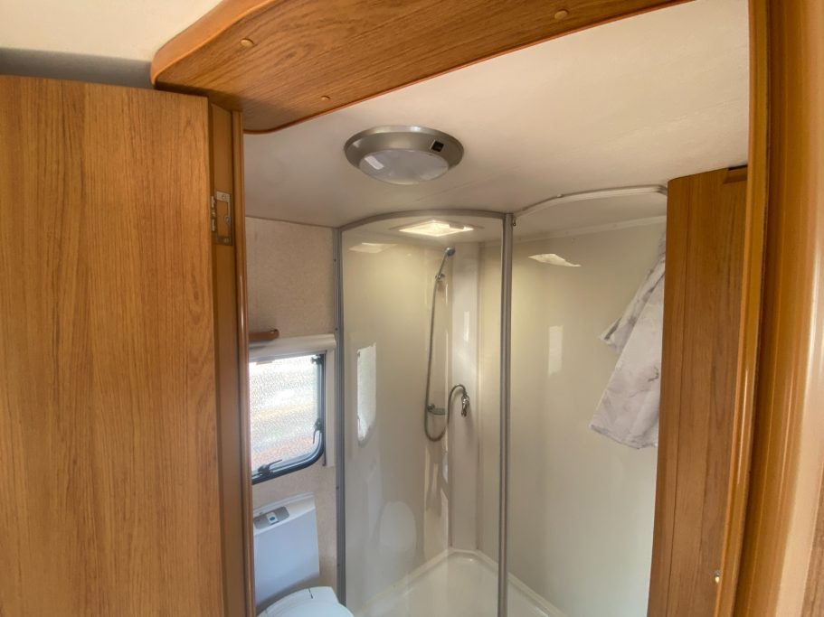 A clean, compact shower area with curved glass doors and wood accents.