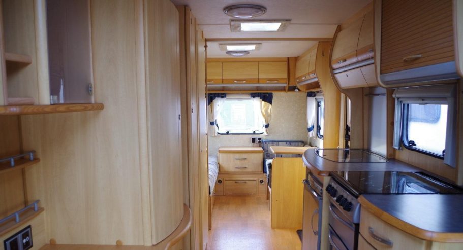 Interior of a modern caravan with wooden cabinetry and kitchen appliances.