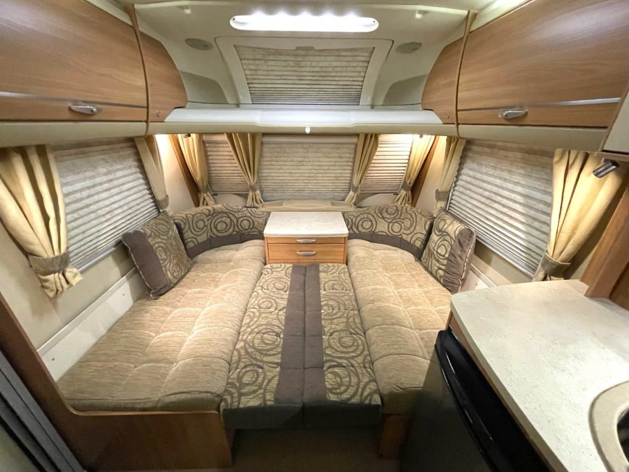 Interior of a caravan featuring a U-shaped seating area and a central table.