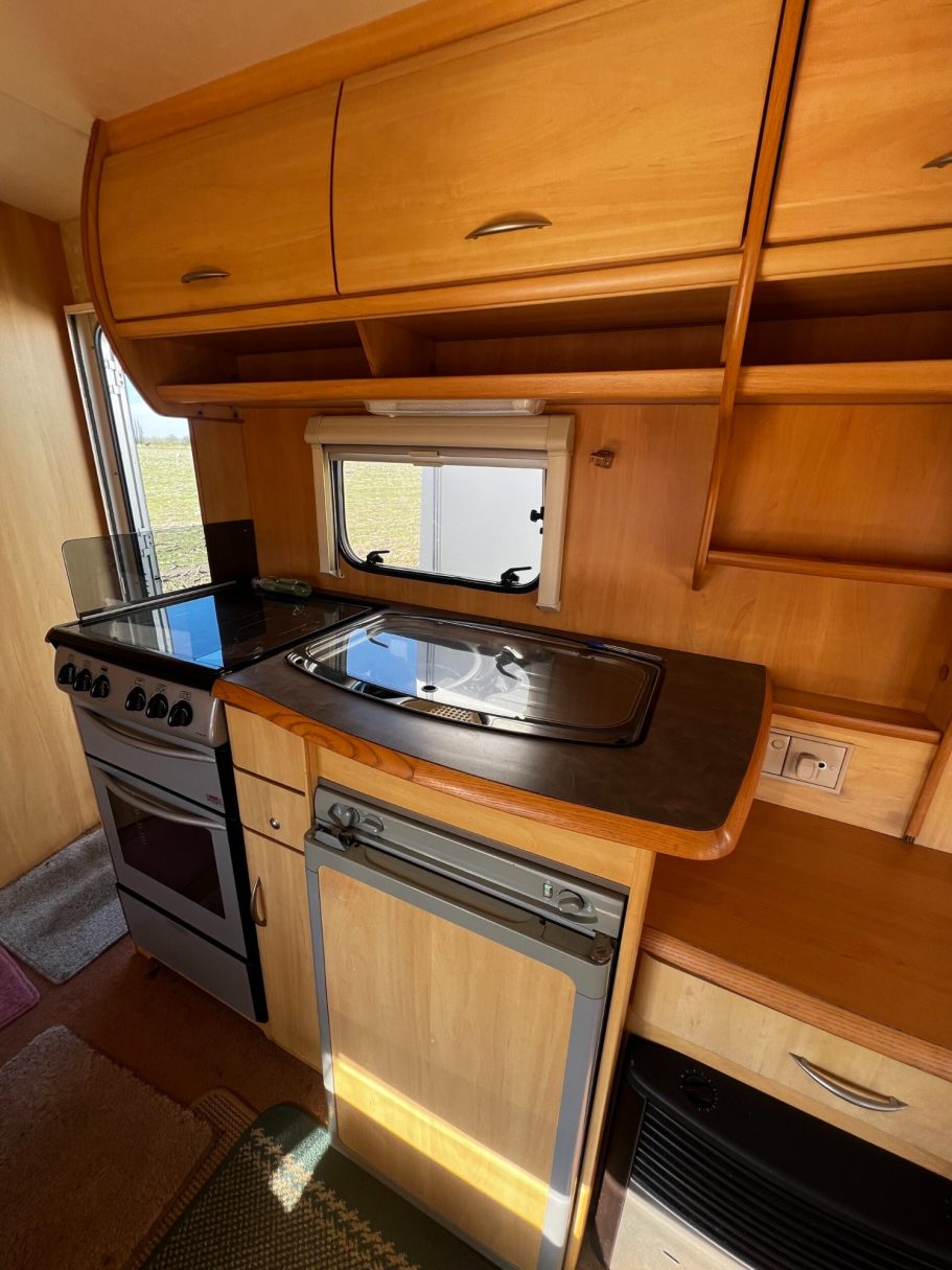 Compact kitchen with a stove, sink, and wooden storage cabinets.