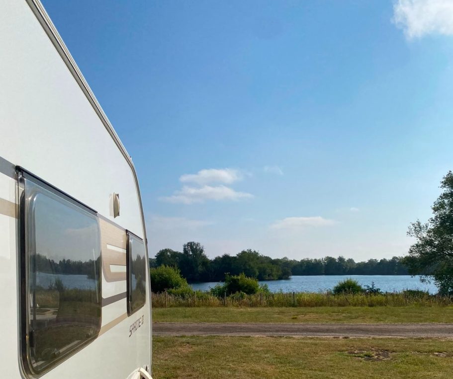 SquaredAway rental caravan pitched beside a lake at a campsite.